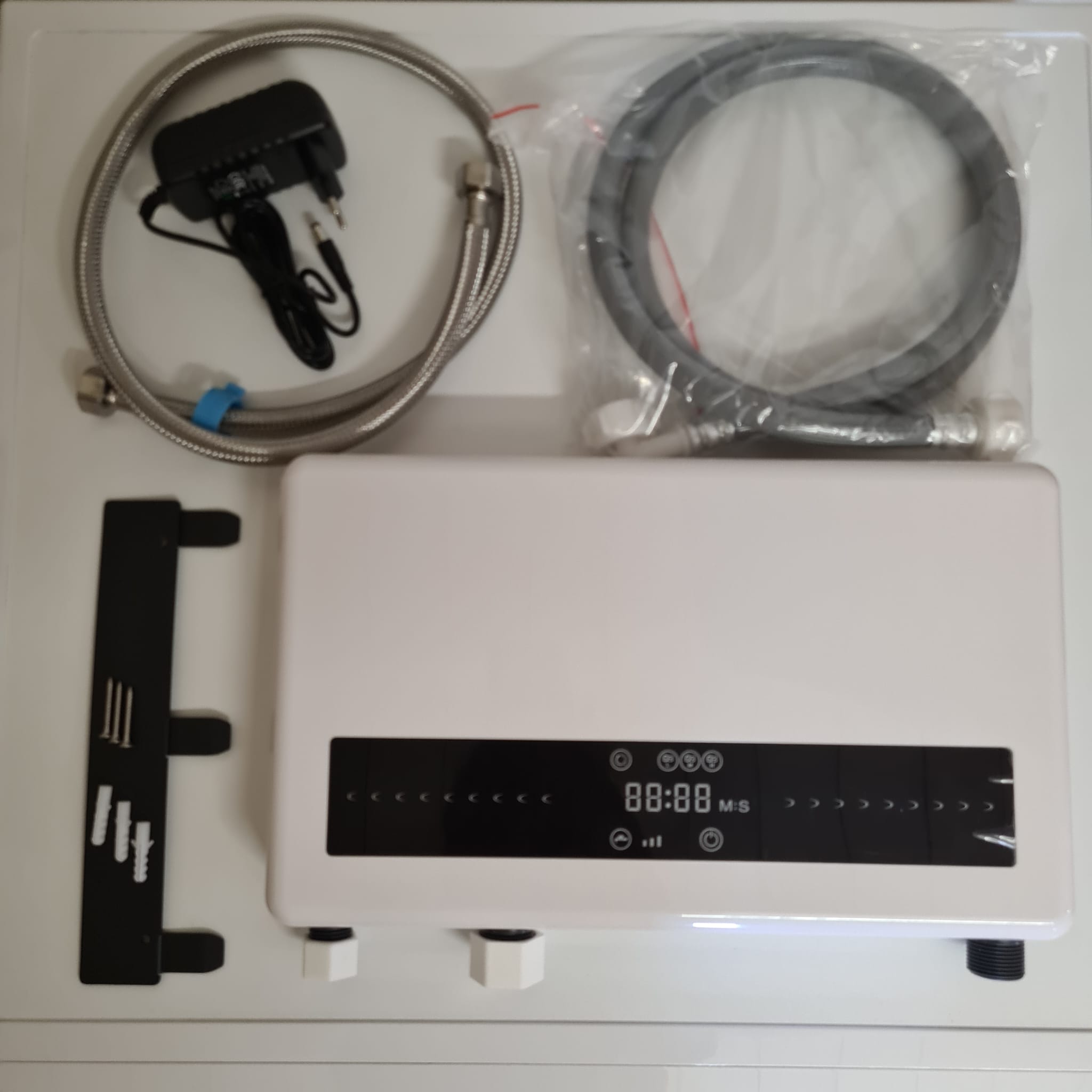 White system with power adapter, hoses and mounting hardware in the packaging